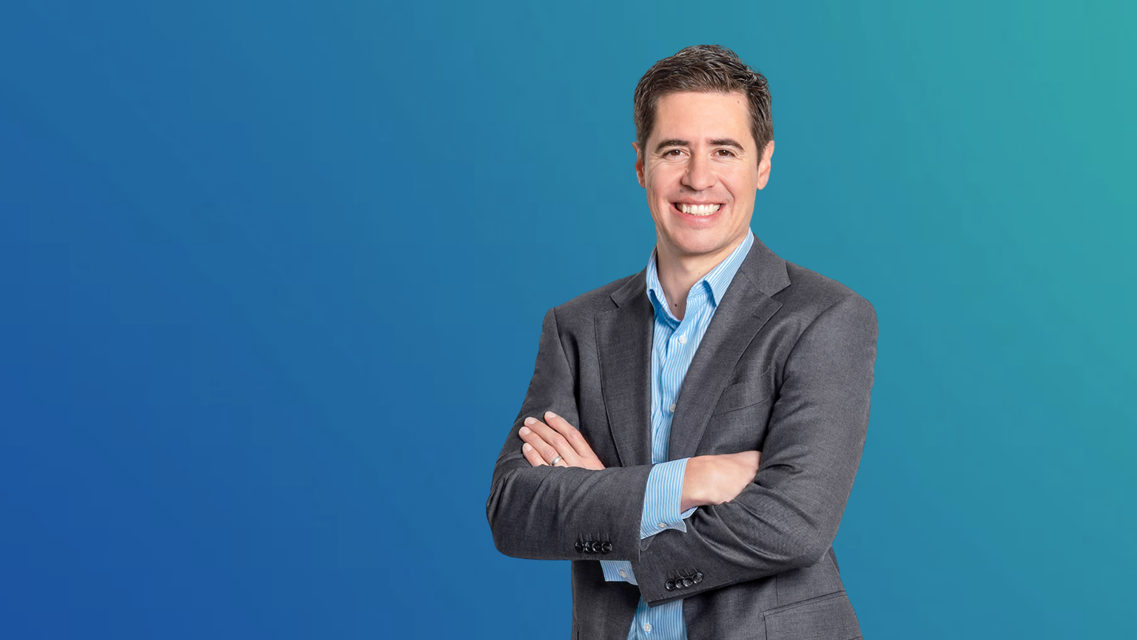 Manuel Kugler, Programme Manager Data &amp; AI / Advanced Manufacturing, in a grey suit against a blue background