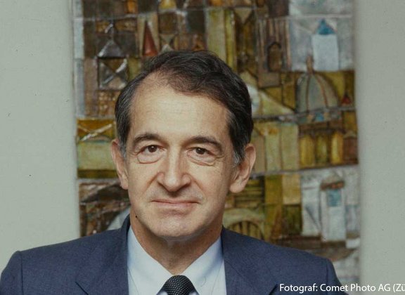 Urs Hochstrasser in a suit in front of an abstract painting