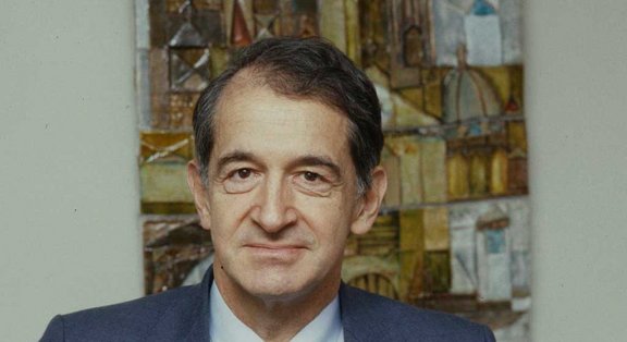 Urs Hochstrasser in a suit in front of an abstract painting