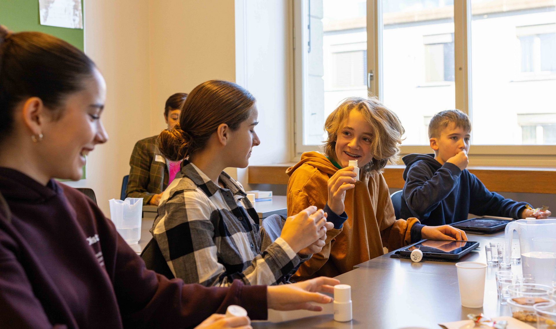 Schüler:innen in einem Klassenzimmer experimentieren am TecDay und lachen.