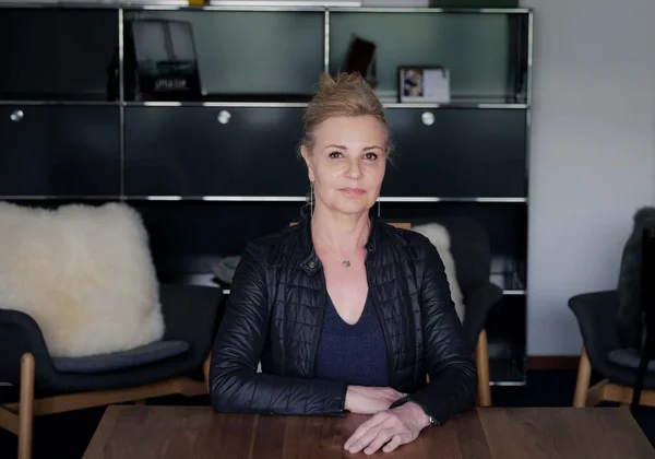 Frau in schwarzer Jacke sitzt an einem Tisch