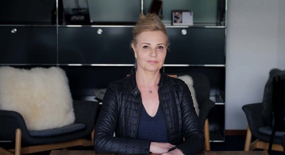 Frau in schwarzer Jacke sitzt an einem Tisch