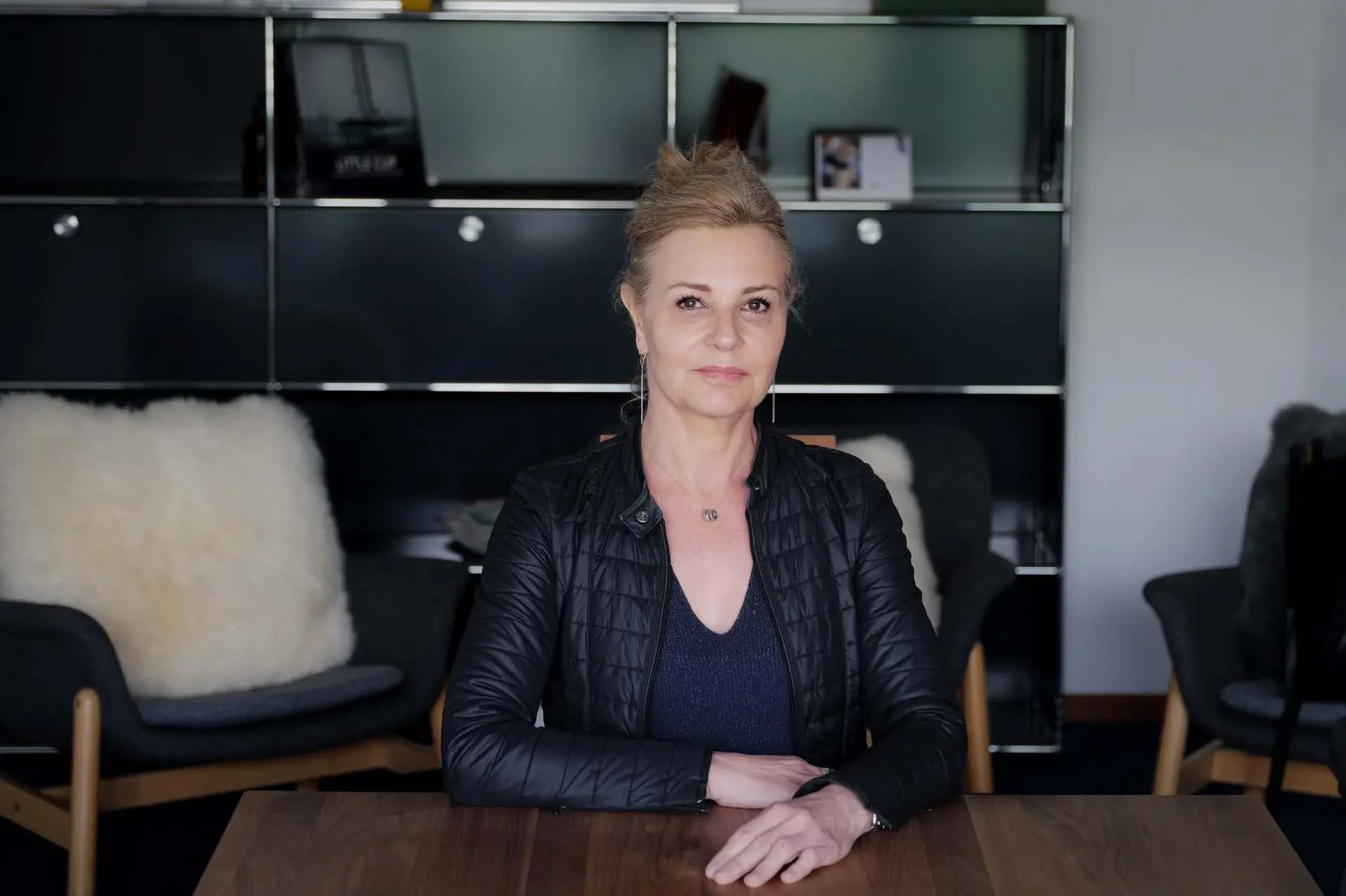 Frau in schwarzer Jacke sitzt an einem Tisch