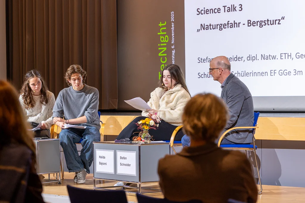 Panel discussion on natural hazards with three students on the left and an expert on the right of the stage.