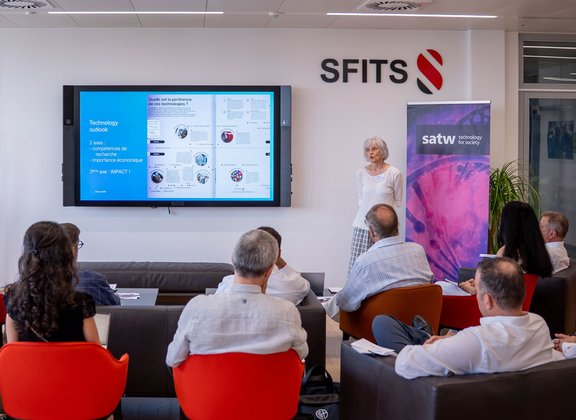 A presentation in a modern conference room with participants and a speaker