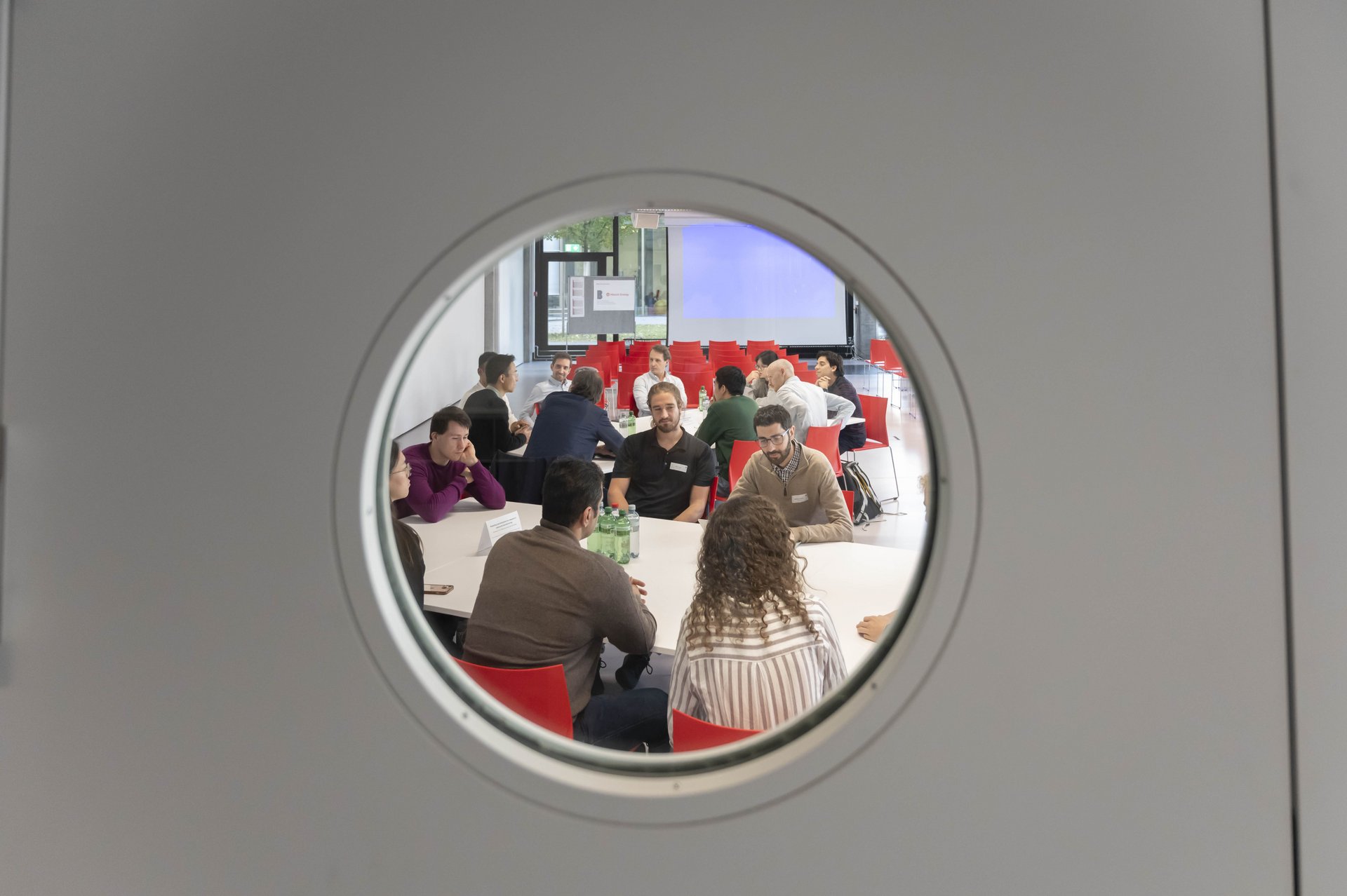 People in meeting seen through porthole