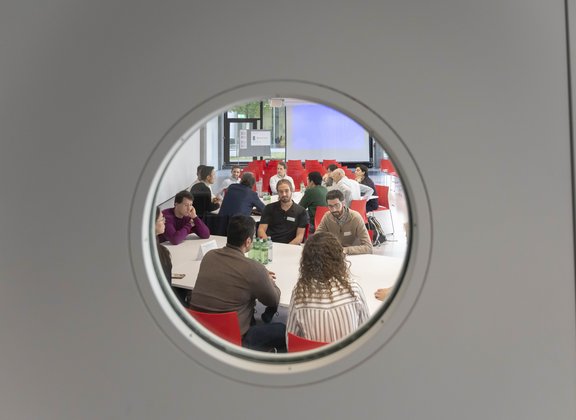 People in meeting seen through porthole