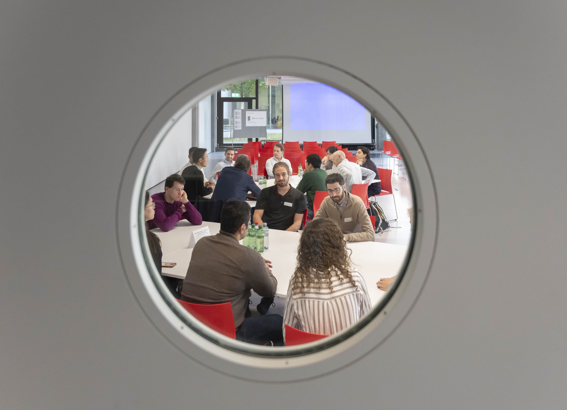 People in meeting seen through porthole