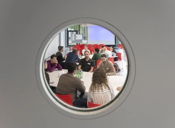 People in meeting seen through porthole
