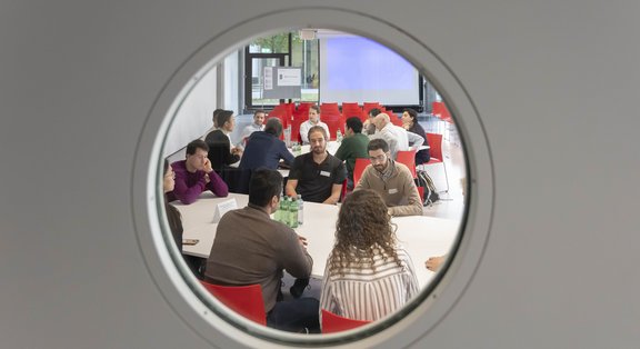 People in meeting seen through porthole