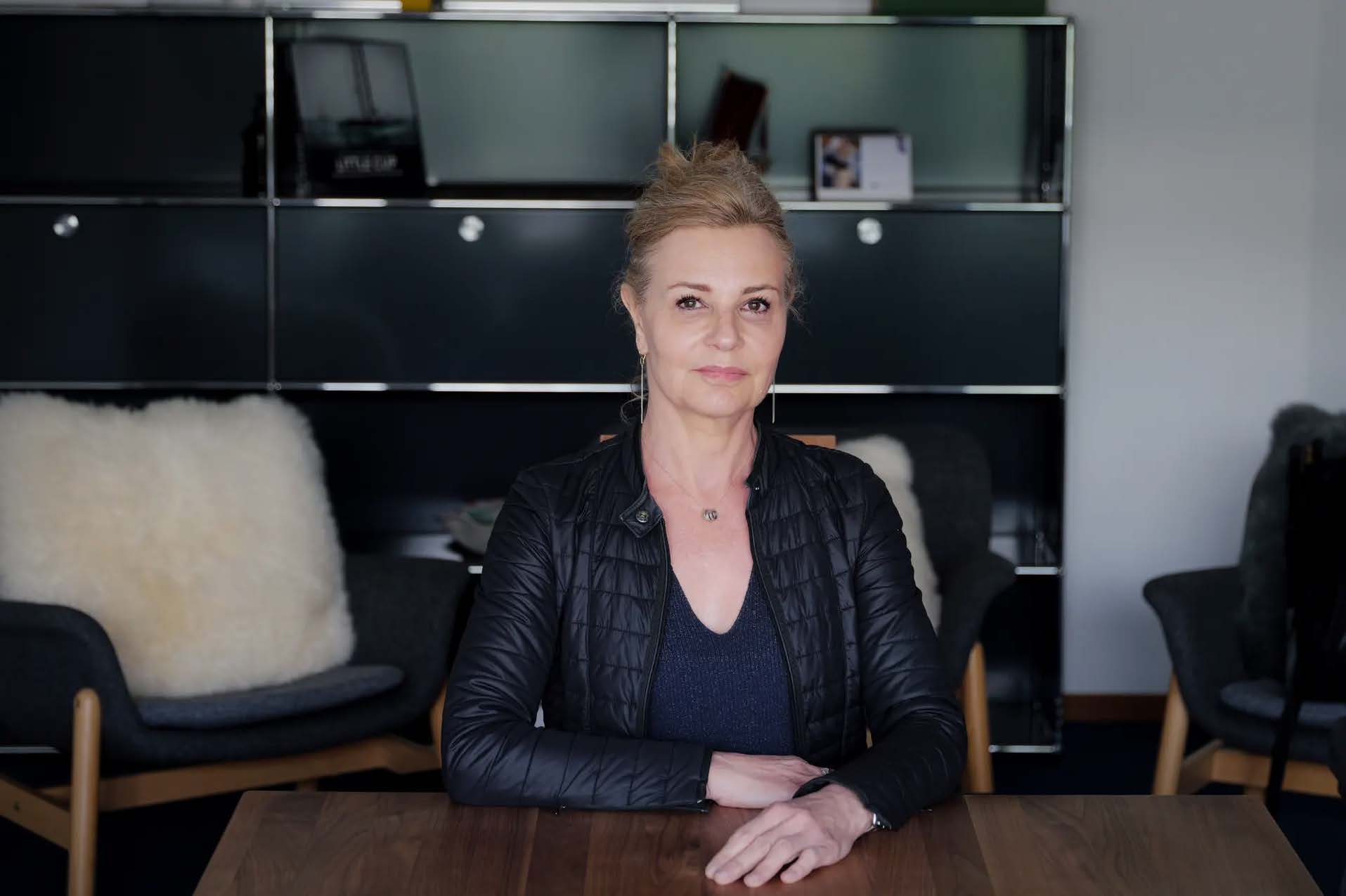 Frau in schwarzer Jacke sitzt an einem Tisch